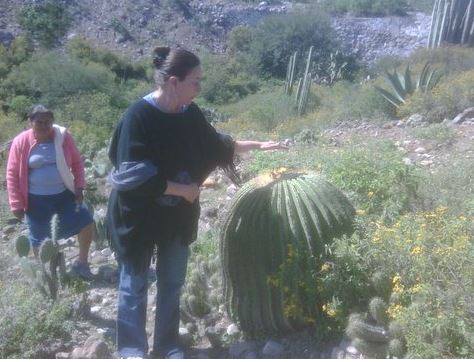 A woman is standing next to a large green cactus
