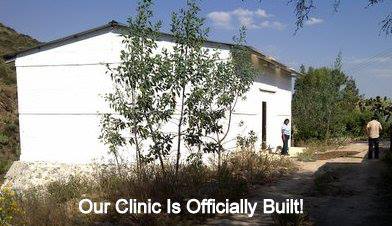 A white building with the words `` our clinic is officially built '' written on it.