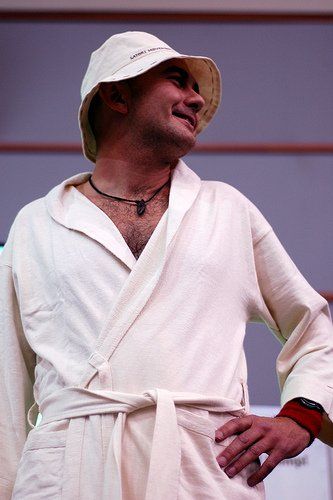 A man wearing a robe and hat is standing with his hands on his hips.