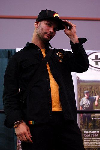 A man wearing a hat and a black jacket adjusts his hat.