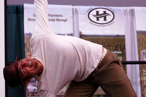 A man is doing a yoga pose in front of a sign that says farmers trial hemp