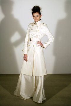 A woman is wearing a white trench coat and wide leg pants.