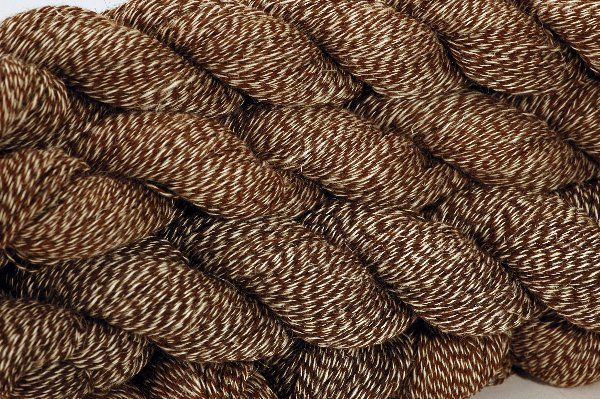 A close up of a pile of brown yarn on a white surface.