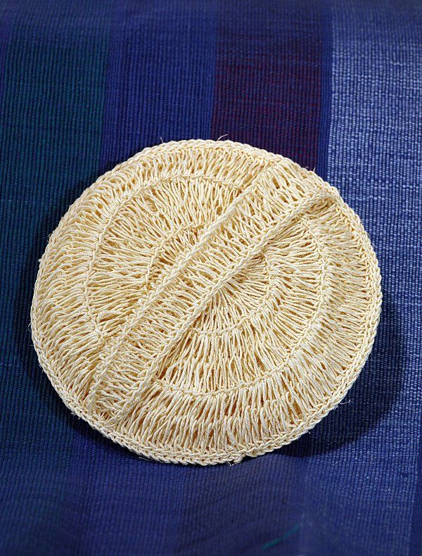 A crocheted hat is sitting on a blue cloth.