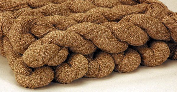 A close up of a pile of brown yarn on a white surface.
