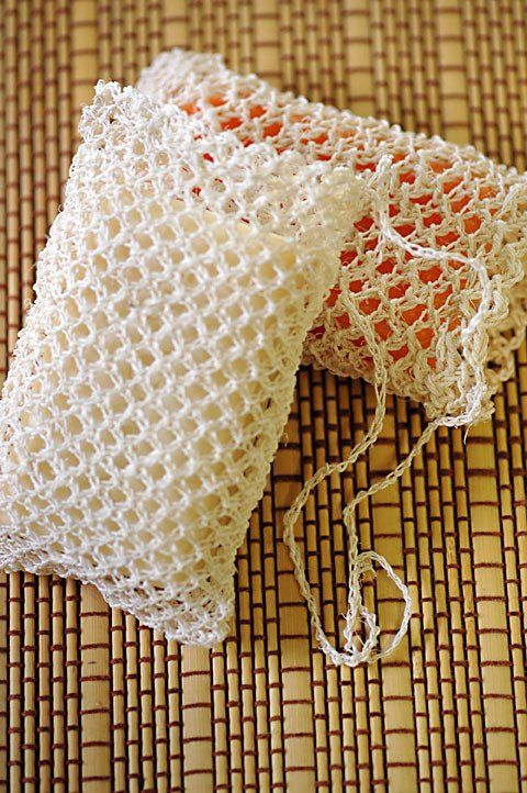 A pair of crocheted bags sitting on top of a bamboo mat.