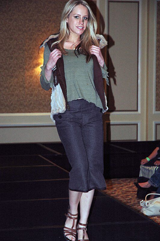 A woman is walking down a runway wearing a vest