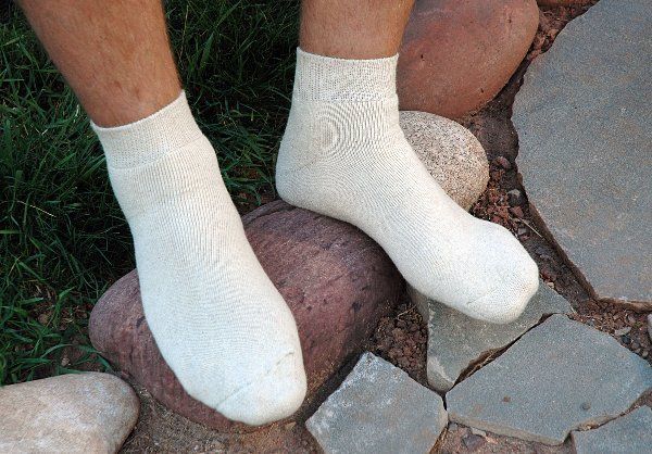 A person wearing white socks is standing on a rock.