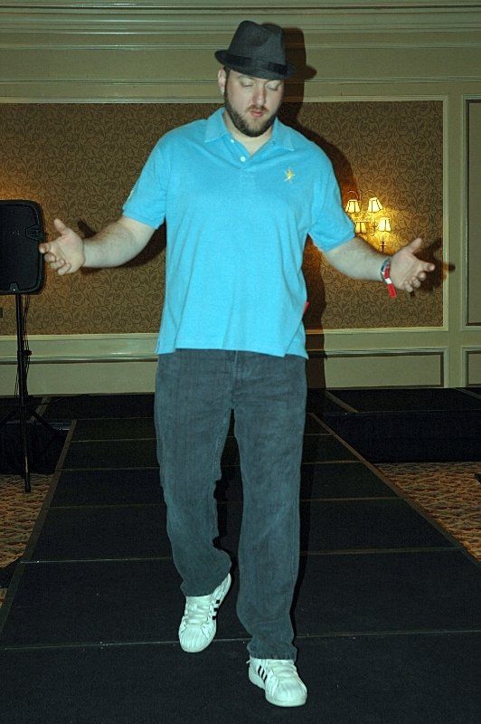 A man wearing a hat and a blue shirt is walking down a runway