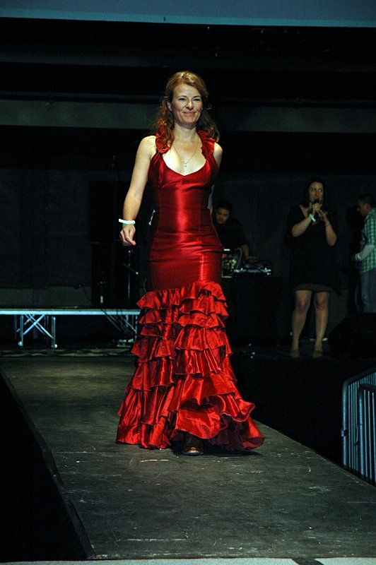 A woman in a red dress is walking down a runway.