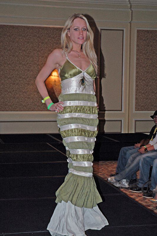 A woman is walking down a runway wearing a green and white dress