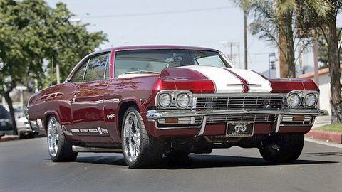 A red and white chevrolet impala is parked on the side of the road