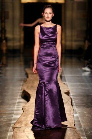 A woman in a purple dress is walking down a runway.