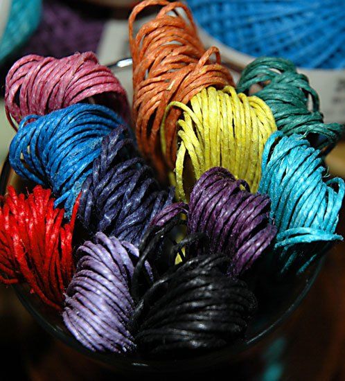 A glass bowl filled with many different colored strings