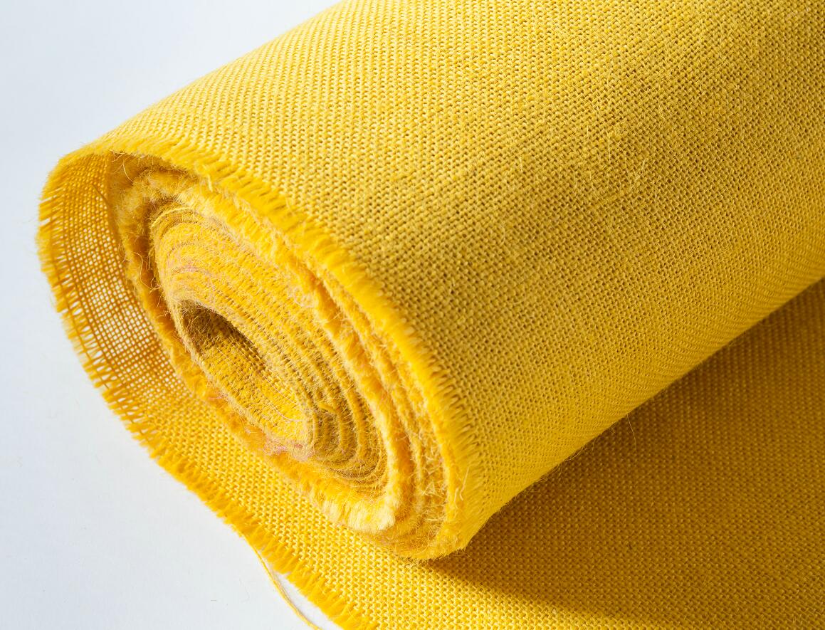 A close up of a roll of yellow fabric on a white surface.