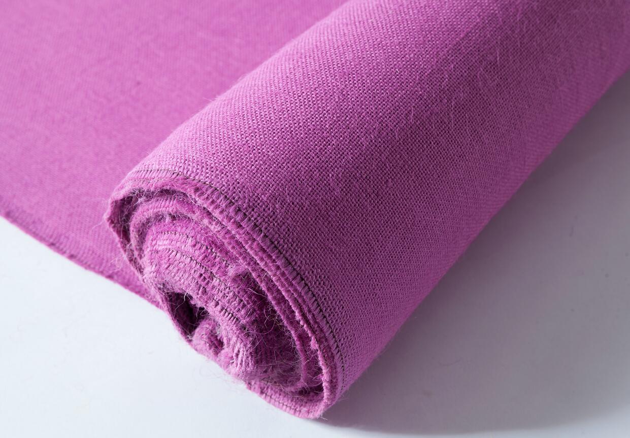 A purple towel is rolled up on a white surface.