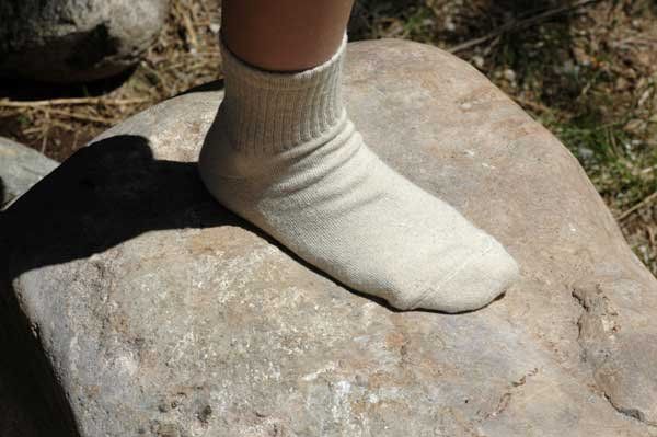 A person wearing white socks is standing on a rock.