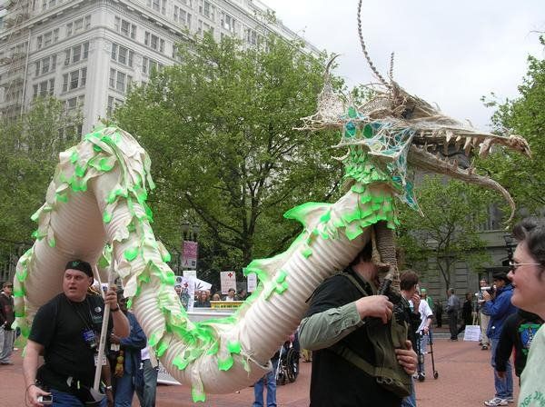 A man in a black shirt is holding a green and white dragon costume