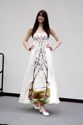 A woman in a white dress is standing with her hands on her hips.