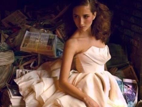 A woman in a white dress is sitting in a pile of books
