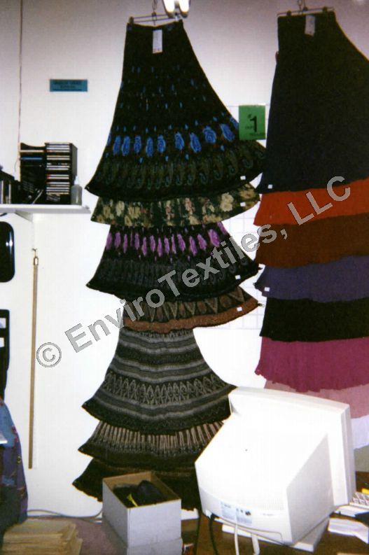 A computer monitor sits in front of a display of sweaters from enviro textiles llc
