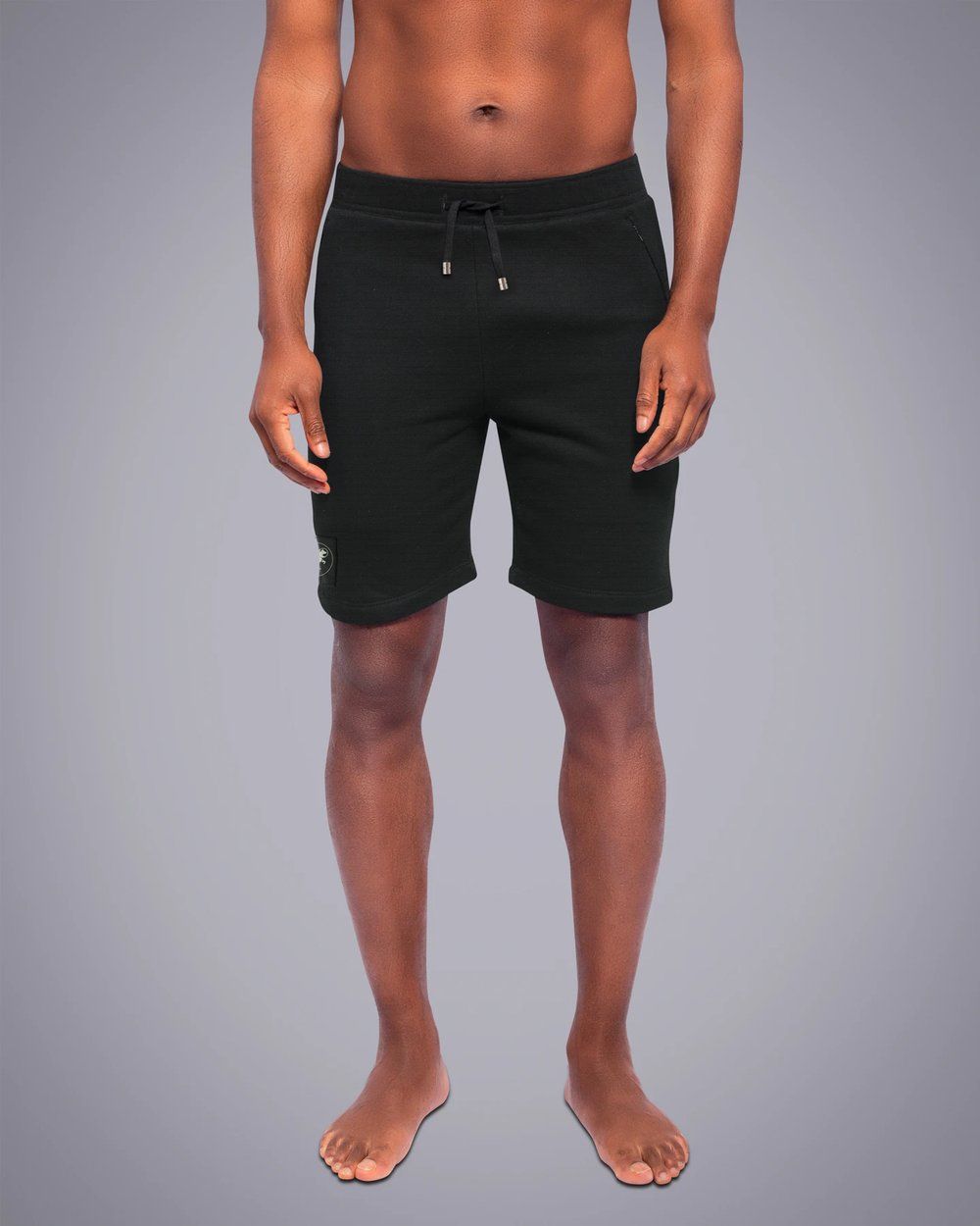 A man without a shirt is wearing black shorts