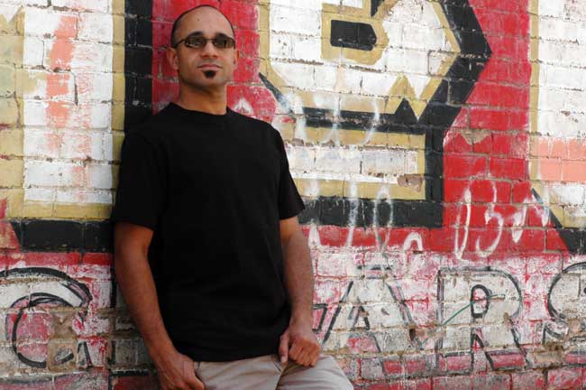 A man leaning against a brick wall with graffiti on it