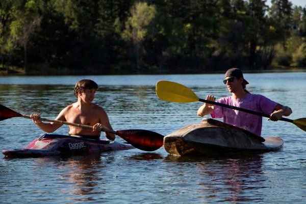 Two people are paddling kayaks on a lake.