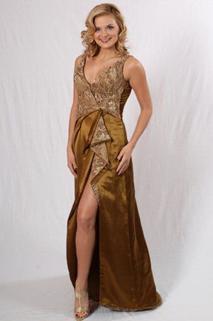 A woman is wearing a long gold dress with a high slit