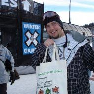 A man is holding a bag in front of a sign that says winter games.