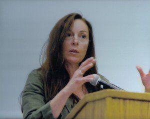 A woman is standing at a podium talking into a microphone.