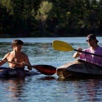 Two men are paddling kayaks on a lake.
