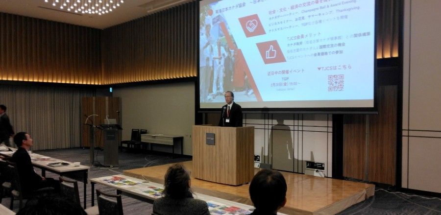 A man is giving a presentation in front of a large screen in a conference room.