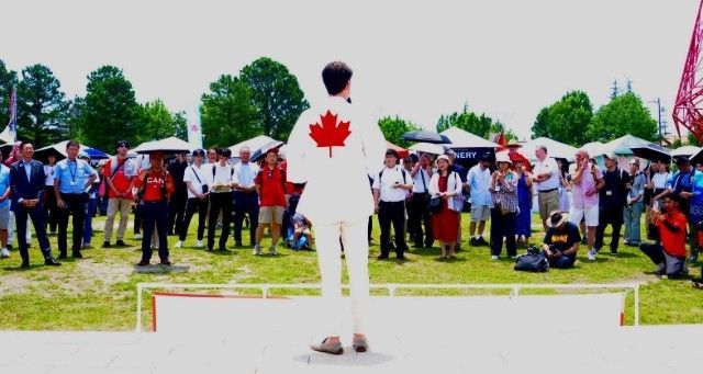 A man with a Canadian flag on his shirt stands in front of a crowd