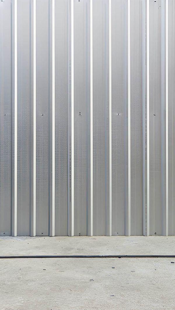 A Close Up of a Metal Wall With a Concrete Floor in Front of It — Rhythm Roofing in Byron Bay, NSW