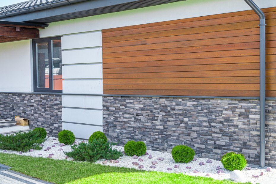 The Front of a House With a Wooden Siding and a Stone Wall — Rhythm Roofing in Yamba, NSW