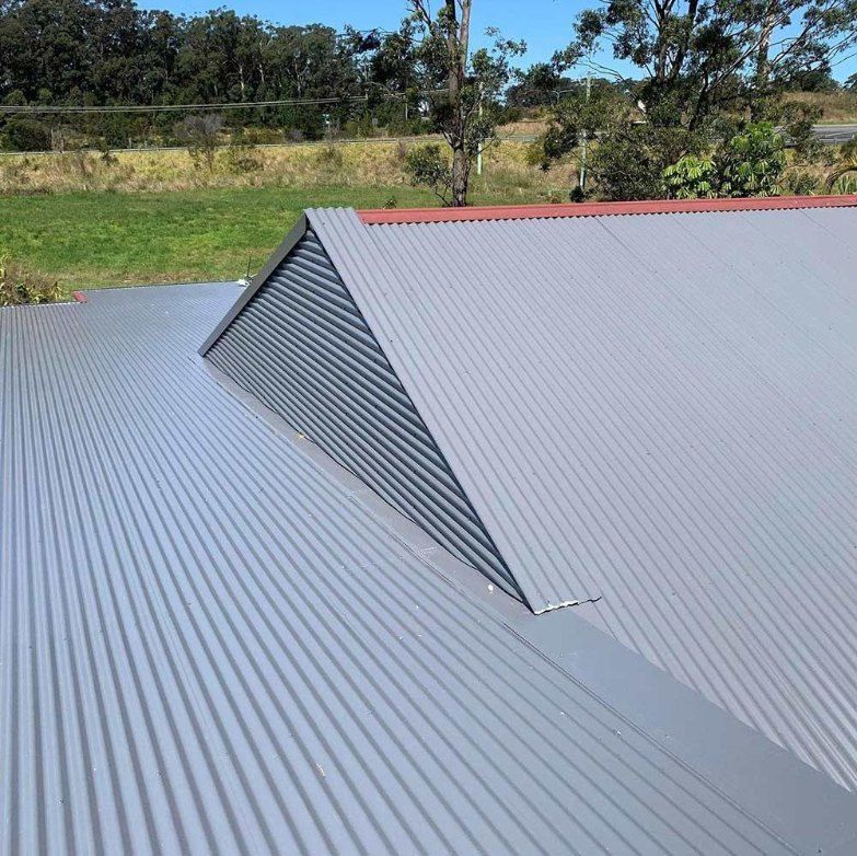 A Gray Corrugated Metal Roof With a Triangle in the Middle of It — Rhythm Roofing in Armidale, NSW