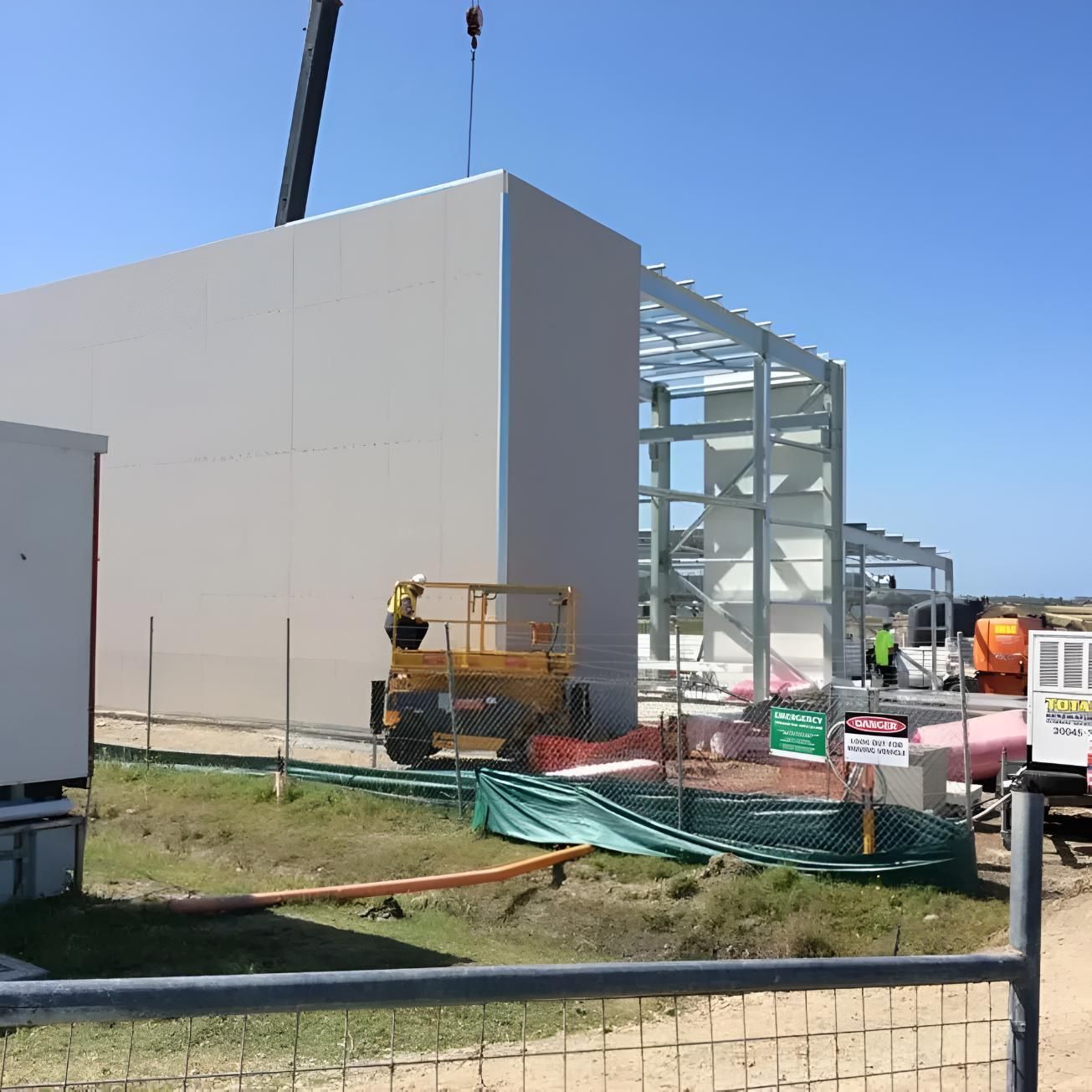 A Large Building is Being Built With a Crane in the Background — Rhythm Roofing in North Boambee Valley, NSW