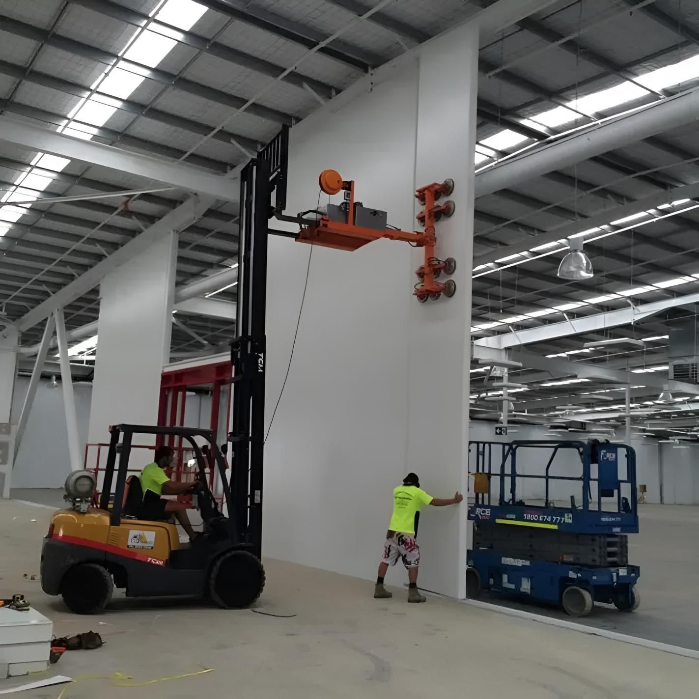 A Man in a Yellow Shirt is Standing Next to a Forklift — Rhythm Roofing in North Boambee Valley, NSW