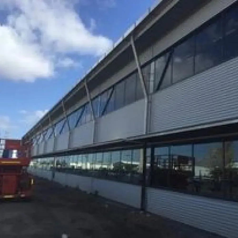 A Large Building With a Lot of Windows and a Red Bus Parked in Front of It — Rhythm Roofing in Ballina, NSW