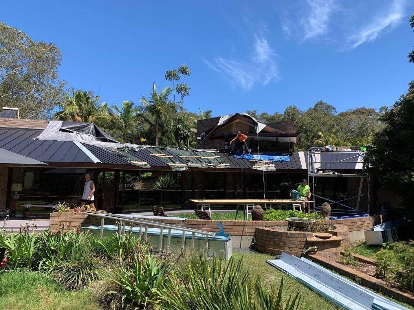 A Man is Working on the Roof of a House — Rhythm Roofing in Silverwater, NSW
