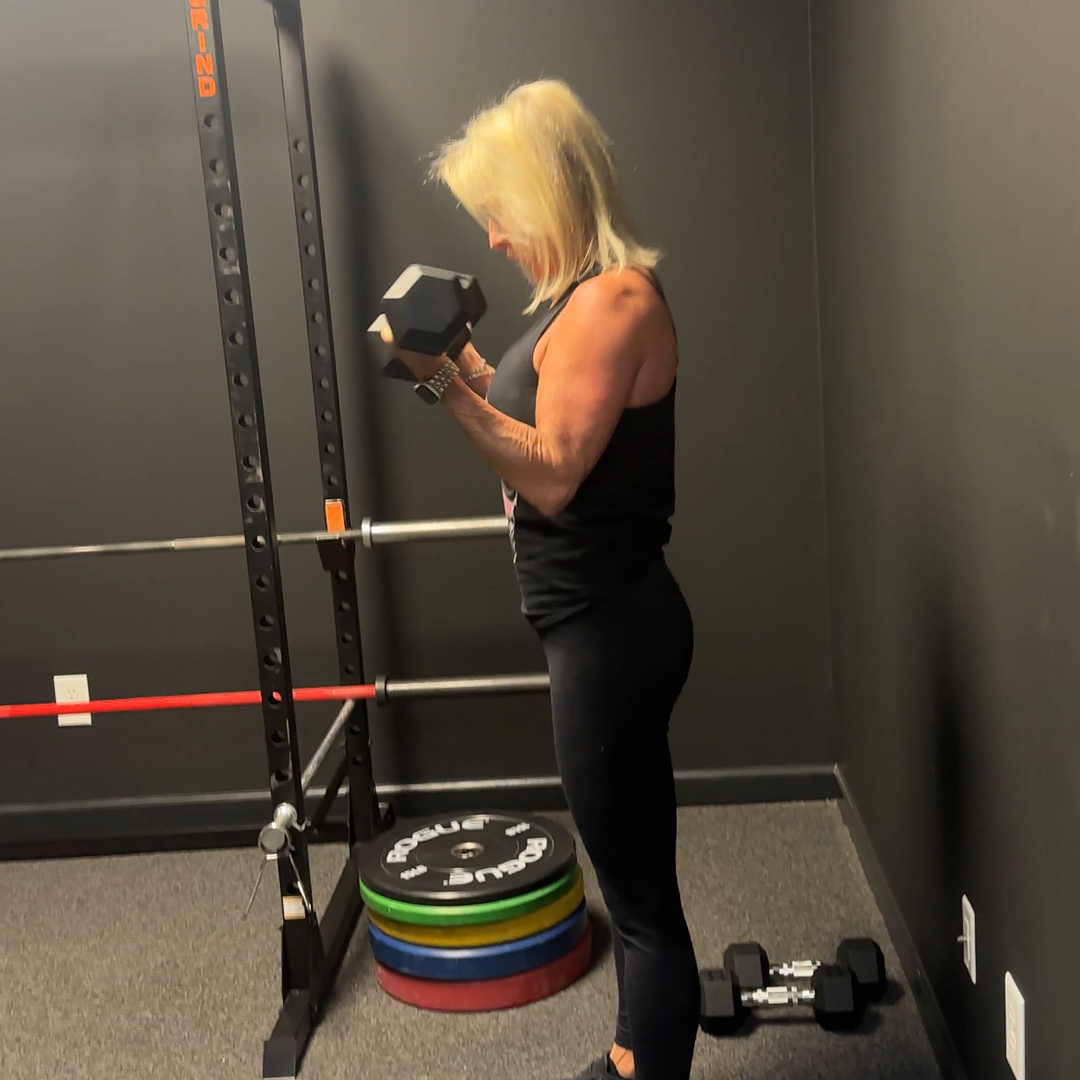 A woman is lifting a dumbbell in a gym