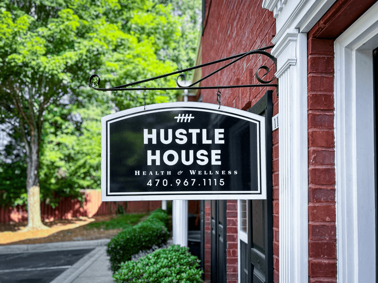 Three women are posing for a picture in front of a hustle house sign.