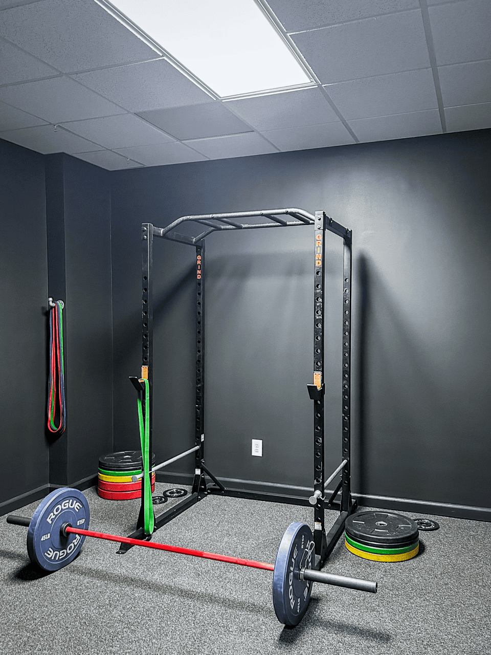 A gym with a bench and a barbell rack.