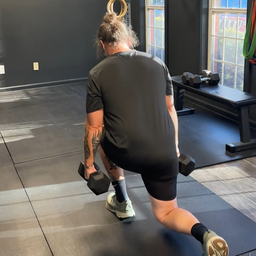 A man squatting down holding a pair of dumbbells