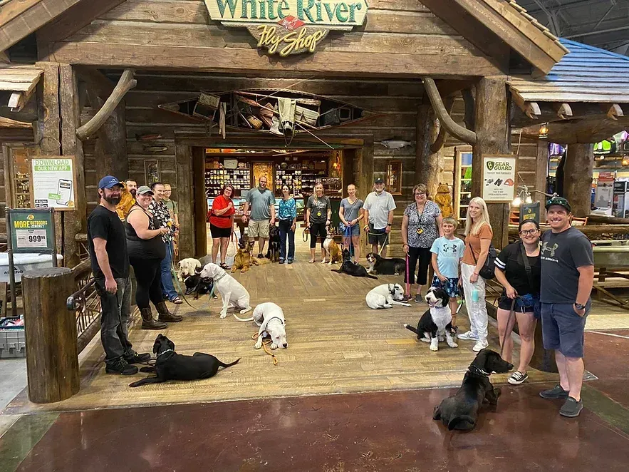 A group of people and dogs are standing in front of a store.