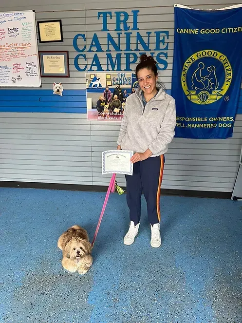 A woman is standing next to a small dog on a leash.