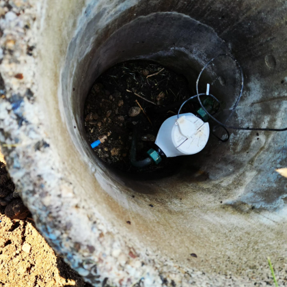 Looking down into a concrete well, with a white sensor and attached black tubing.
