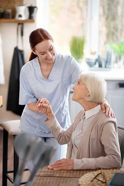 Smiling caregiver supporting pensioner after surgery 
