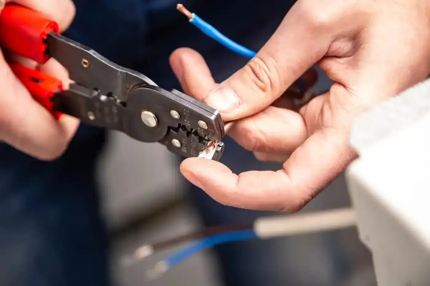 Mani che utilizzano spelafili per preparare i cavi elettrici.